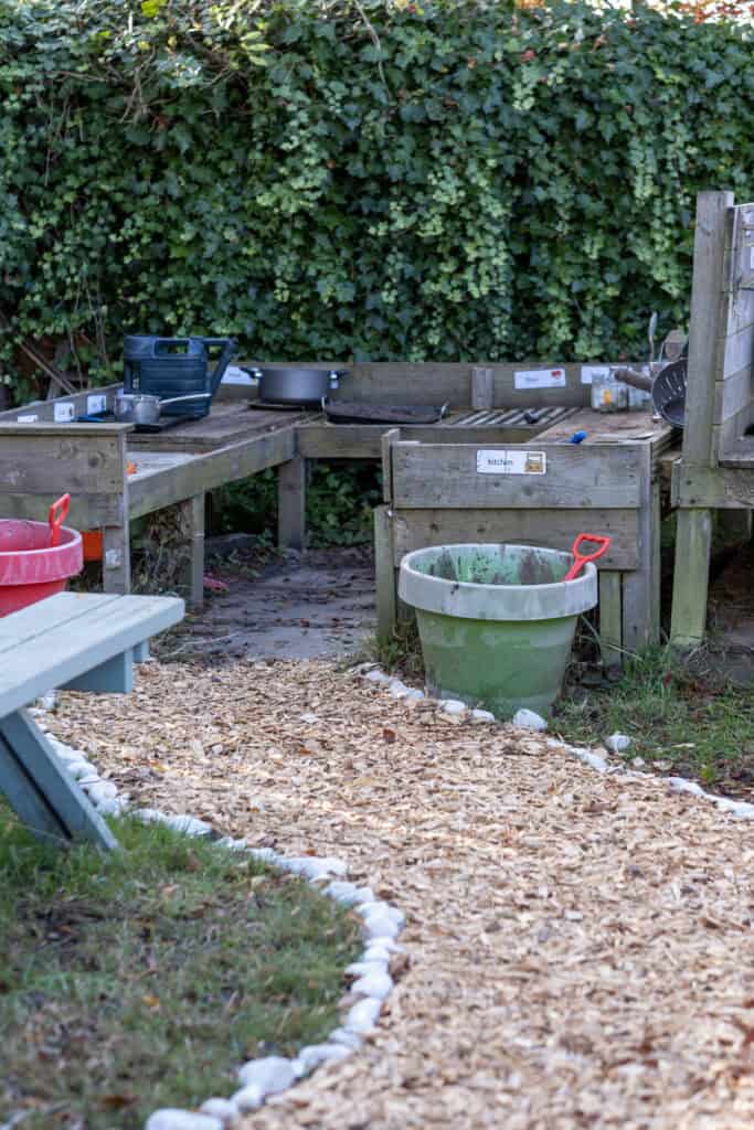 Bright outdoor play area at Thrive Childcare, featuring wooden kitchen playsets and sandbox for children’s creative and imaginative learning activities.