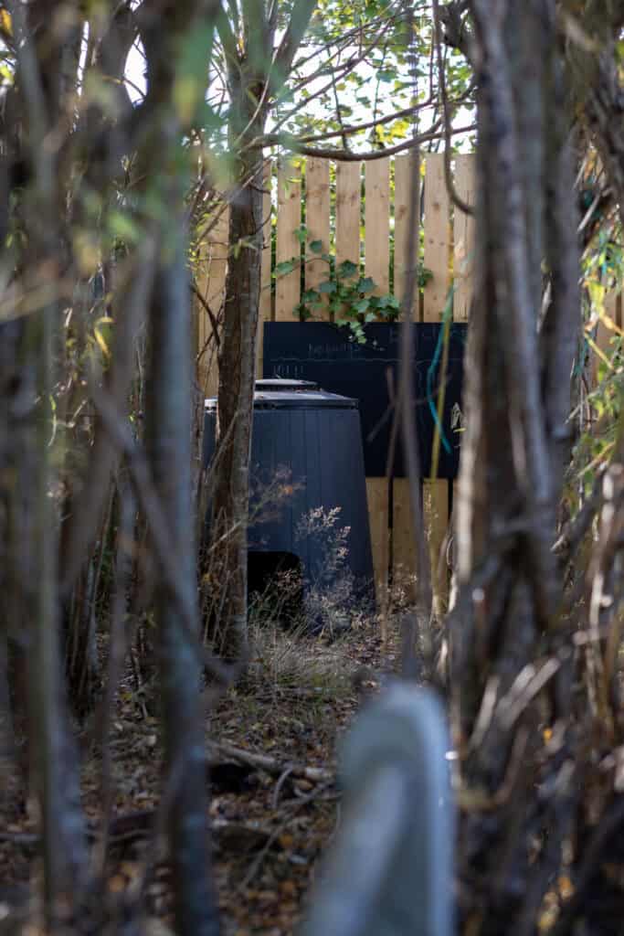 A wildlife area at Thrive Childcare featuring natural hedges, trees, and a chalkboard, offering children outdoor nature exploration and environmental learning experiences.