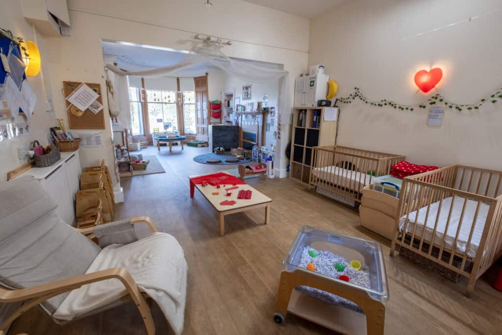 1. Bright and welcoming childcare room at Thrive Childcare with cribs, play areas, and soft lighting for infant and toddler care in a safe, nurturing environment.