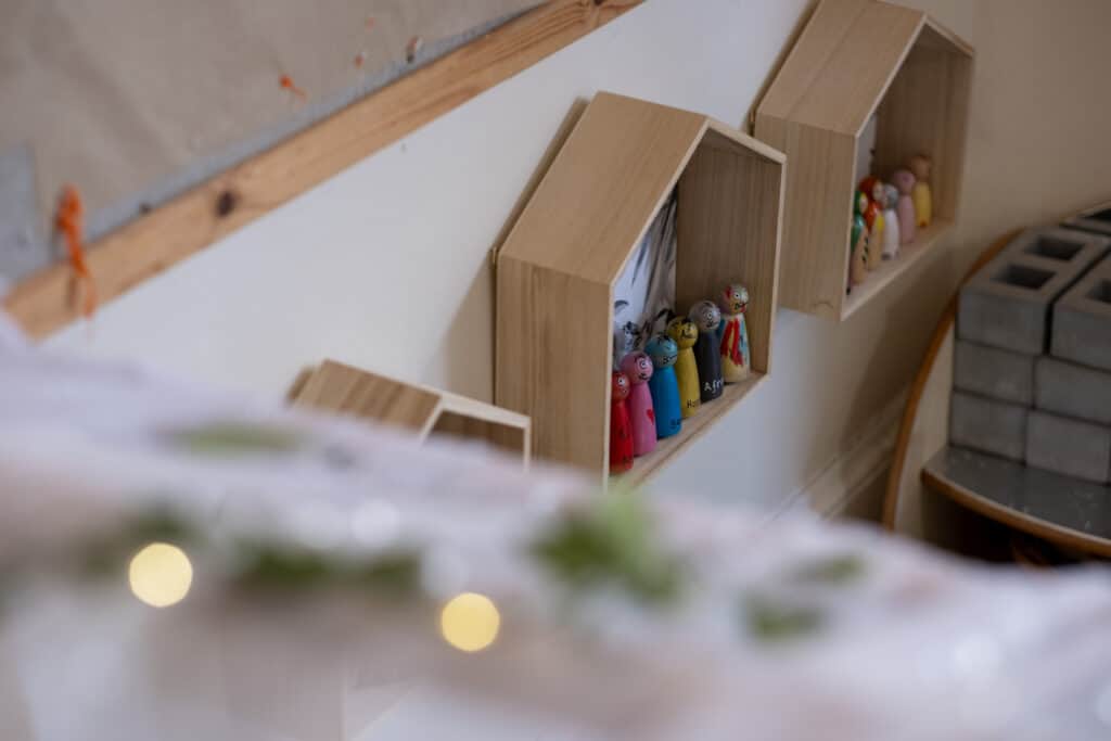 Colourful wooden nesting dolls on wall-mounted shelves in a childcare centre.