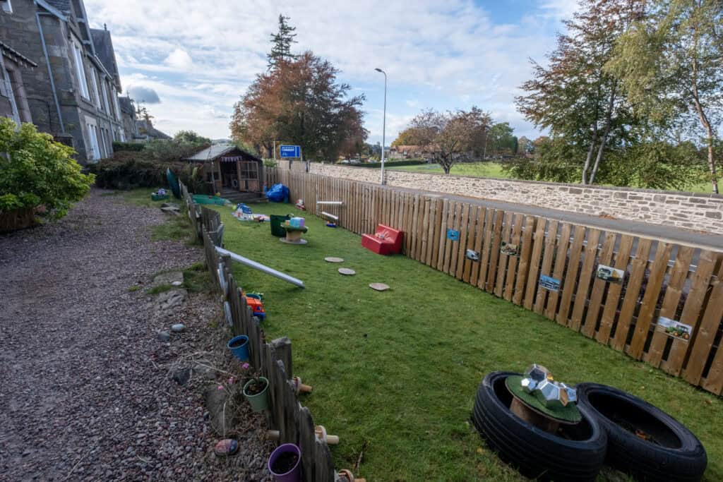 Bright outdoor childcare play area with toys, wooden stepping stones, and tires for children’s activities at Thrive Childcare.