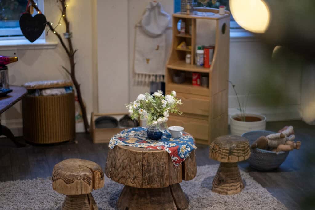 1. Soft indoor play area with wooden furniture, cozy lighting, and decorative plants, creating a warm environment for children's exploration and learning.