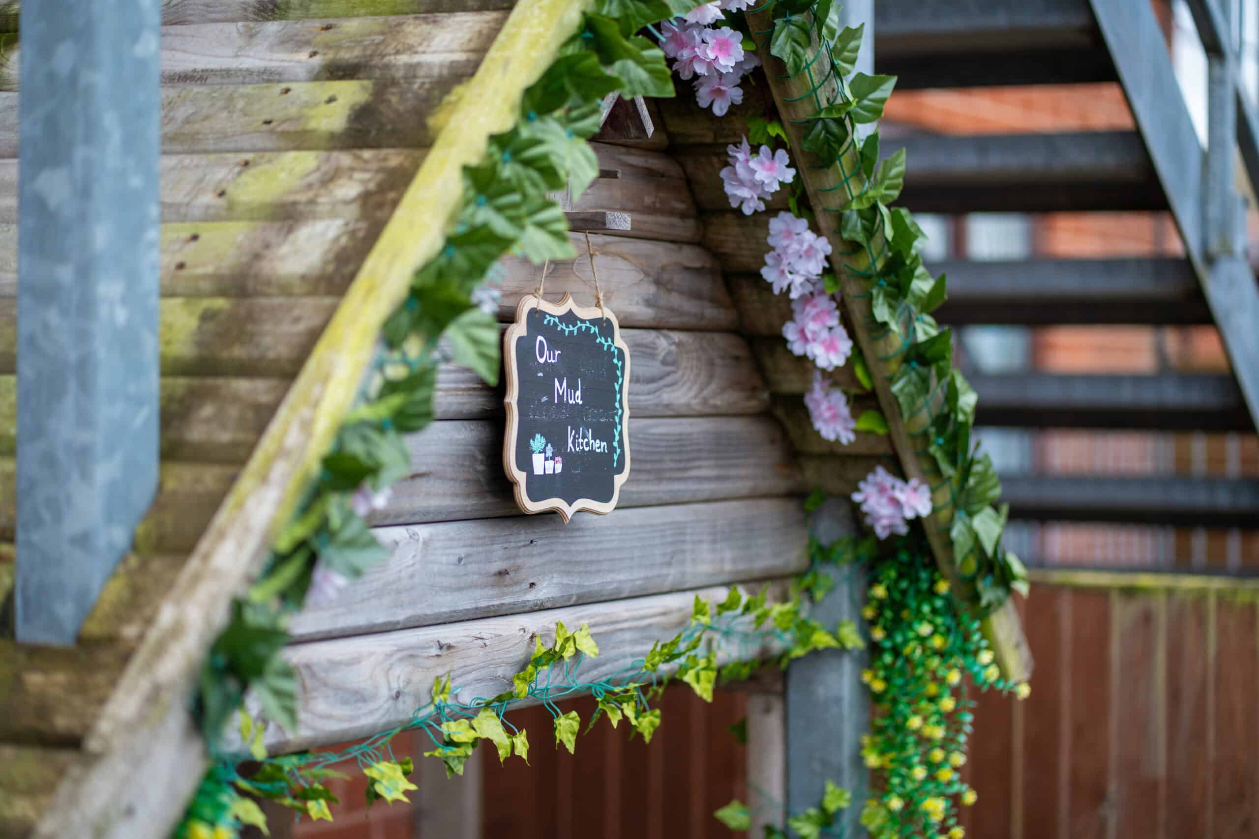 Outdoor play area at Thrive Grosvenor House with decorative flowers and a chalkboard sign.