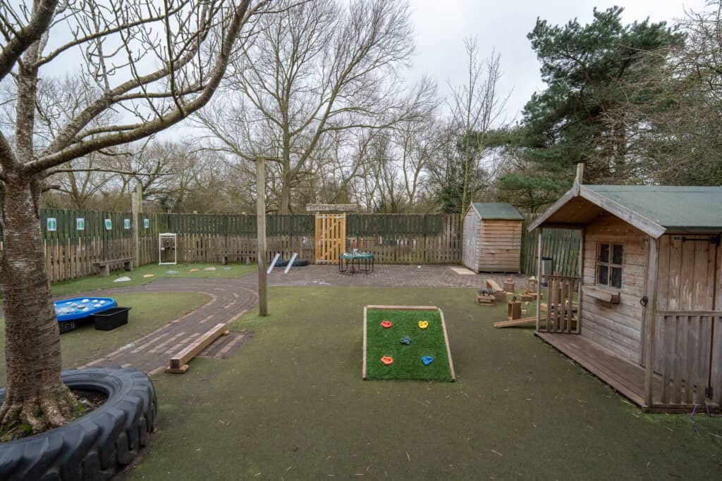 Outdoor play area with trees, wooden playhouses, and activity zones for children.