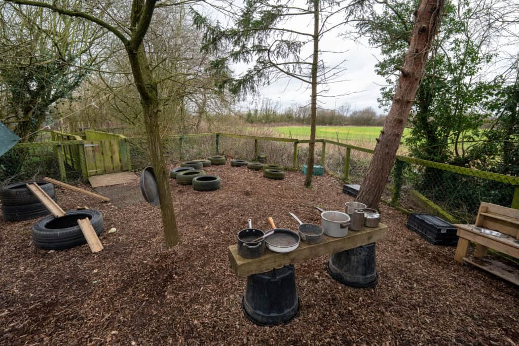 Outdoor play area with tires and wooden structures at Thrive Grosvenor House.