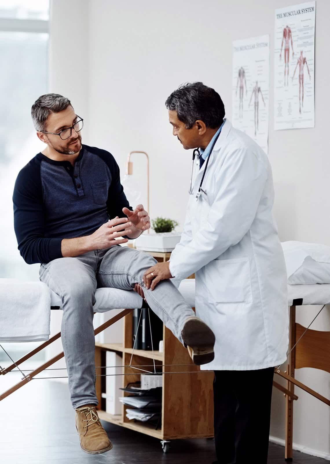 Doctor examining male patient with leg pain in a medical clinic.