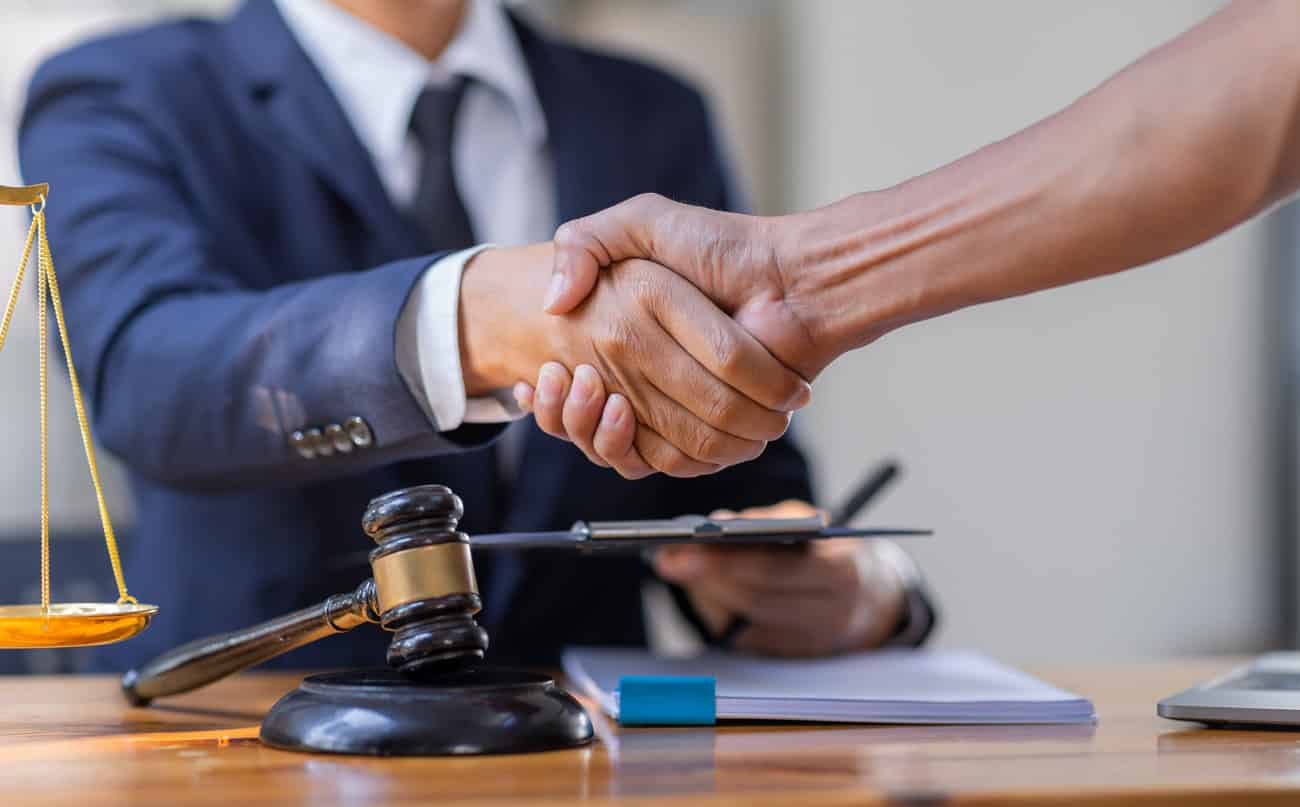 Hand shaking between an attorney and a client representing legal assistance, legal counsel, and client agreement in a law office setting.