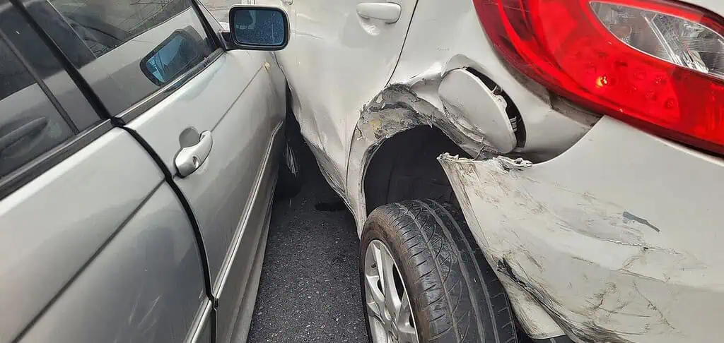 Severe car collision with front and side damage, showing the impact damage between two vehicles involving a silver sedan and a white SUV. Focuses on vehicle repair and accident injury legal needs.