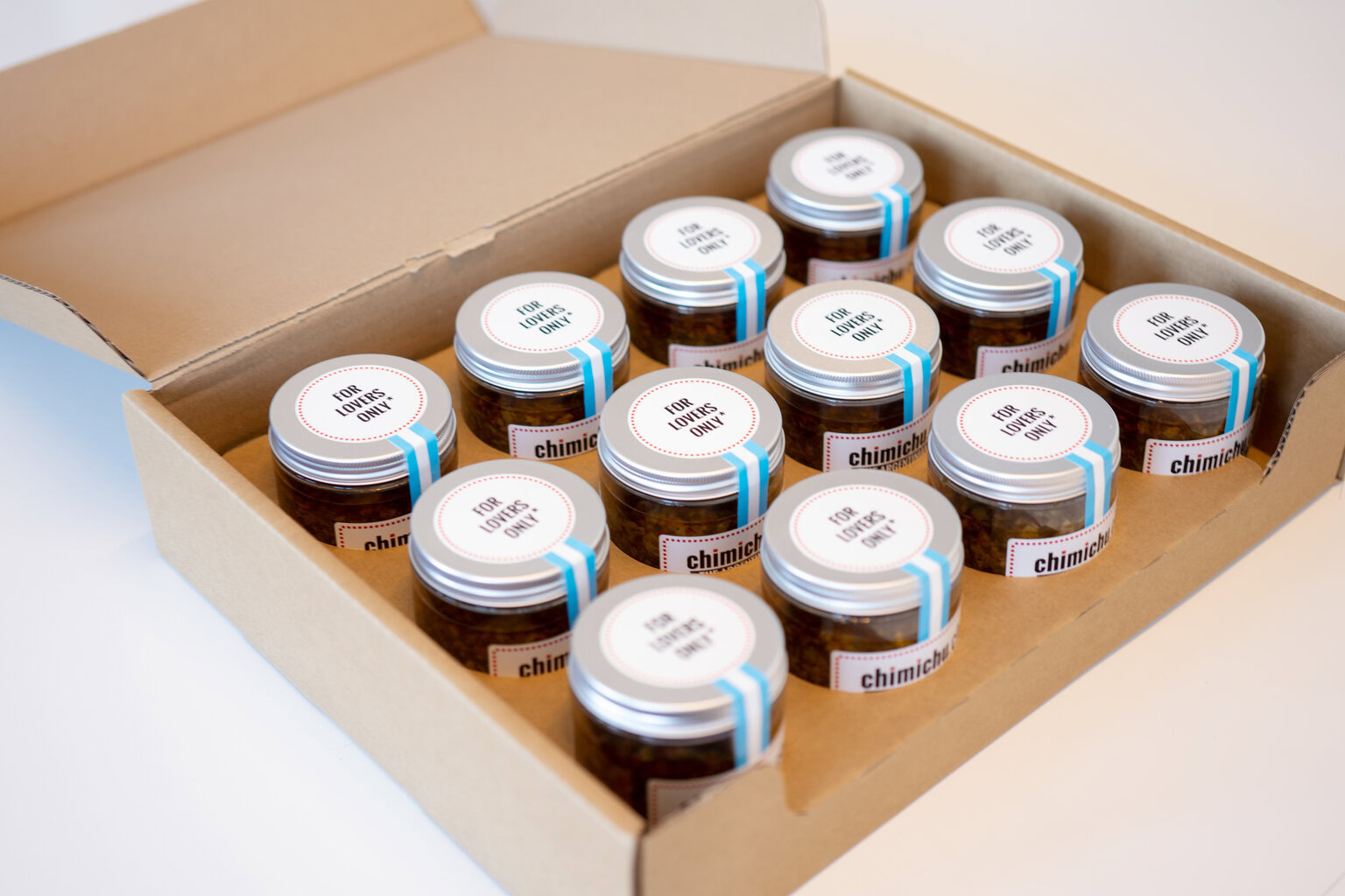 Pequeños tarritos de salsa chimichurri en caja de cartón, ideal para los más gourmets.