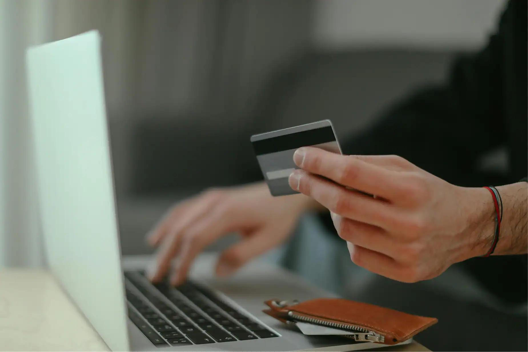 a person holding a credit card and typing on a laptop