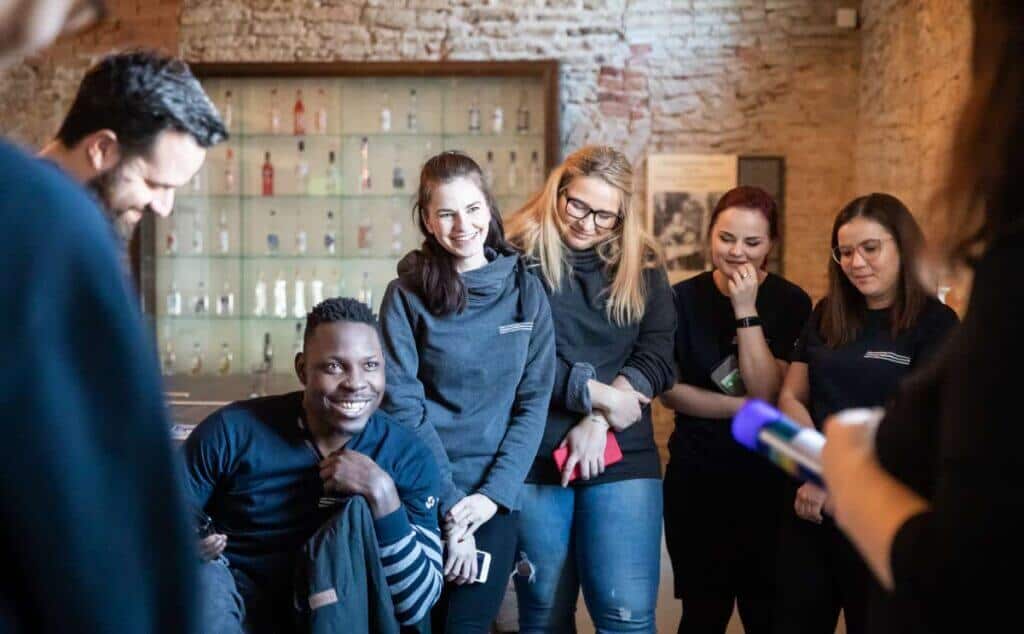 Uma equipe conversando e rindo junta, vestindo camisetas escuras.
