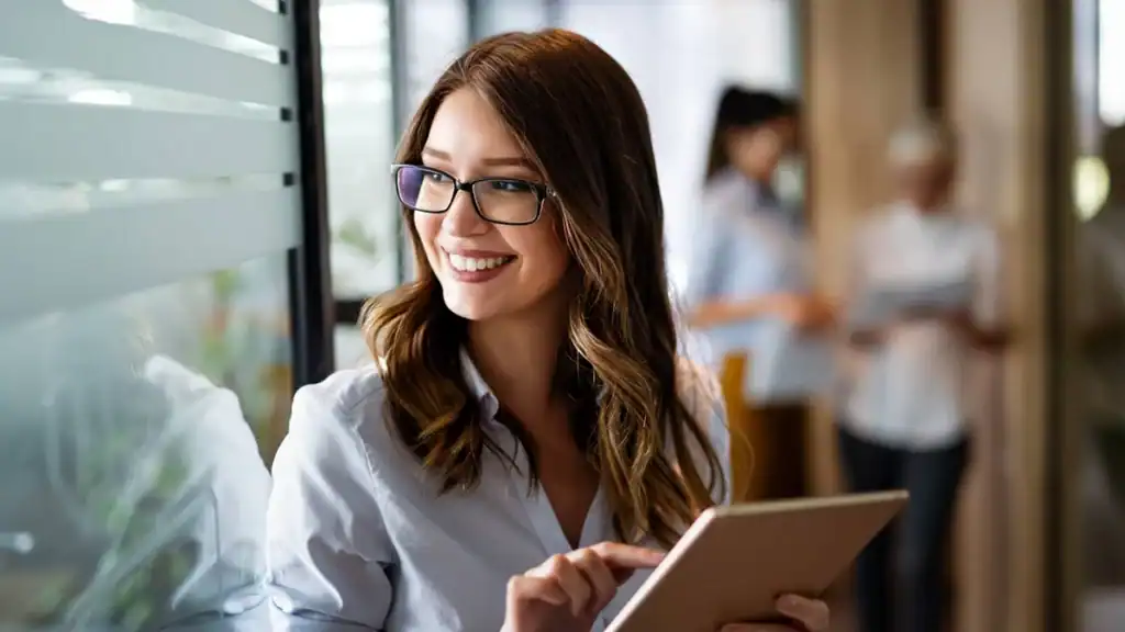 a woman wearing glasses and holding a tablet