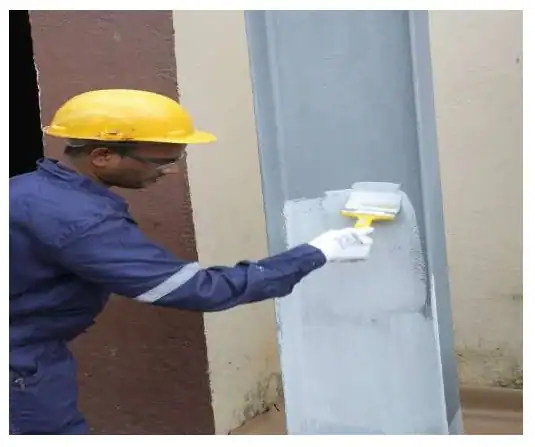Worker applying structural steel coating on steel column for fire protection