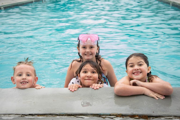 Kids in a pool leaning on the pool side
