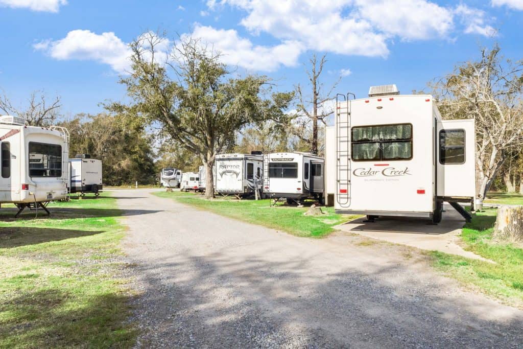 Vinton LA RV Park RVs parked along a gravel road at Vinton LA RV Park in Vinton, Texas, with grass and leafless trees under a partly cloudy sky.