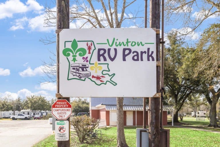 Vinton LA RV Park Vinton RV Park sign with Louisiana map, fleur-de-lis, RV, and flowers in Vinton Texas; private property campground; RVs, trees behind.
