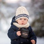 baby bundled up in the snow with a nightingale night nurses mug