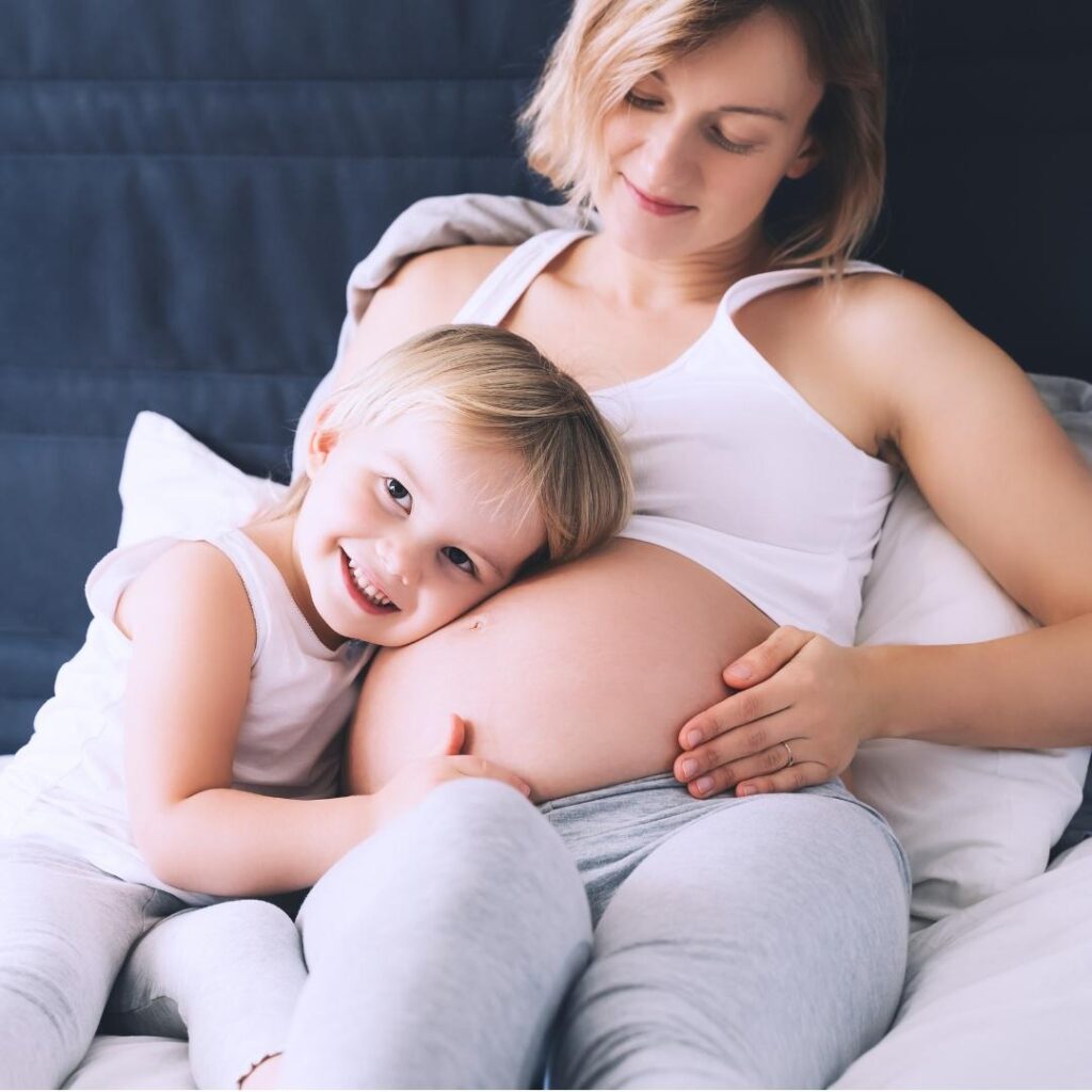 toddler cuddling her moms pregnant belly