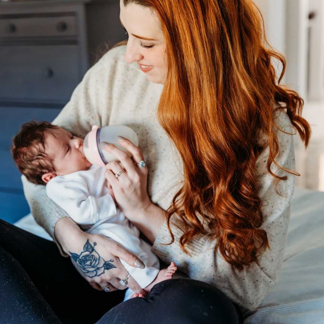 postpartum doula feeding a newborn baby from a comotomo bottle