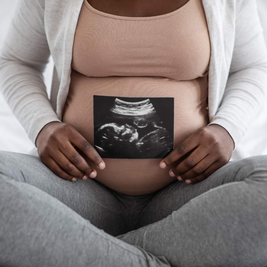 pregnant mom sitting crosslegged with a picture of an ultrasound