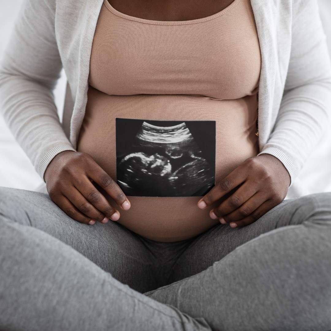 pregnant mom sitting crosslegged with a picture of an ultrasound