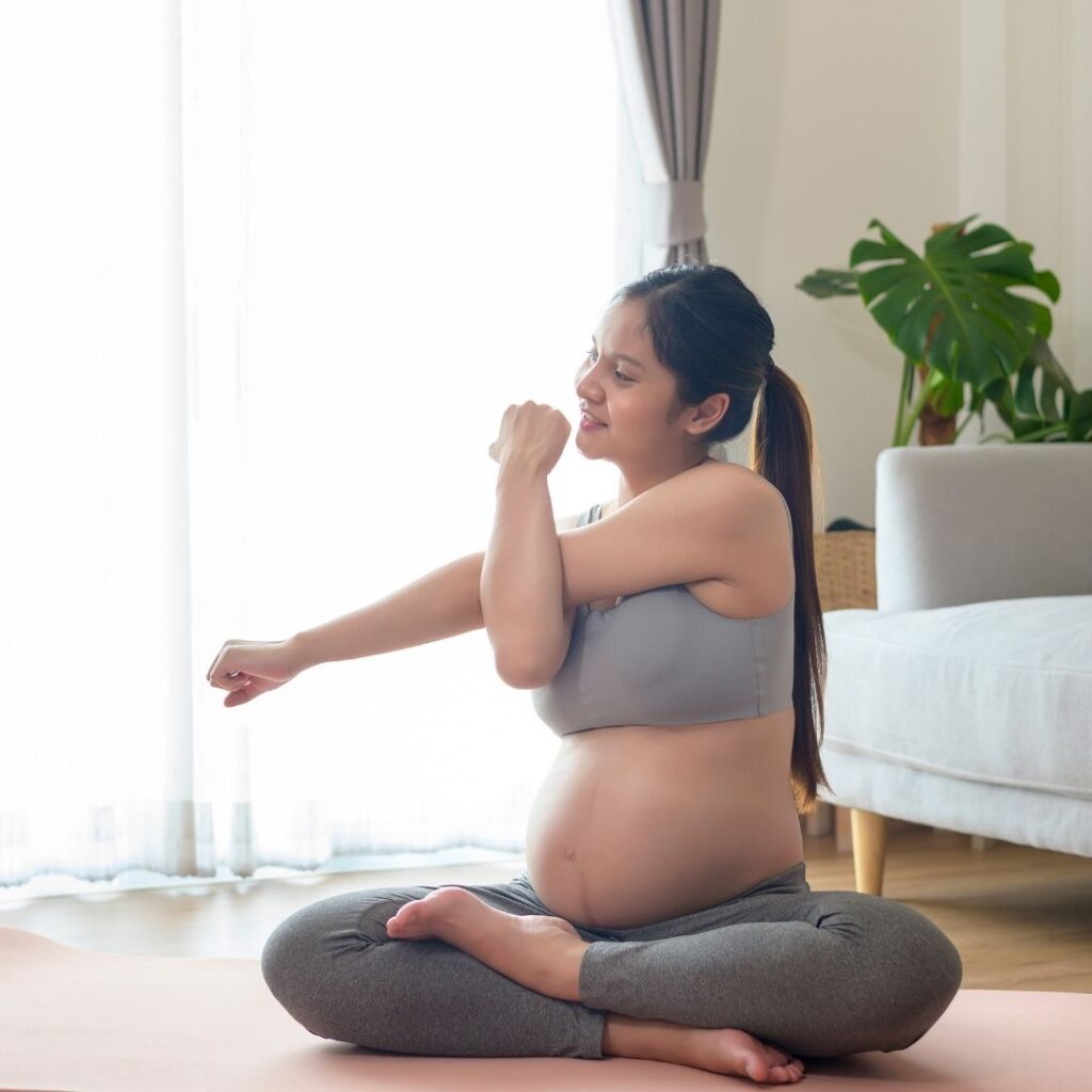 pregnant mom sitting on the floor stretching