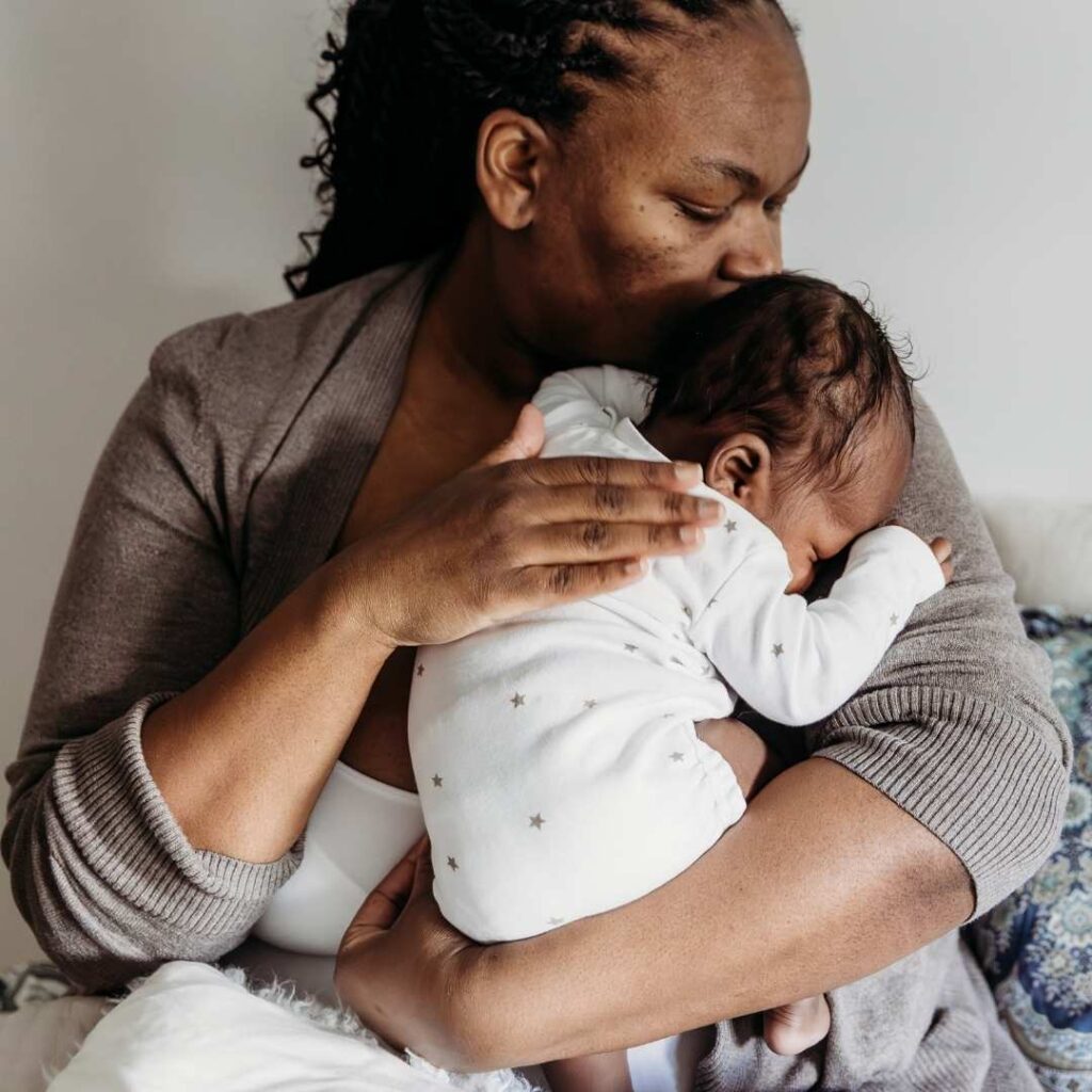 mother cuddling her newborn with her hand on his back
