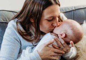 Best Mommy and Me Groups Near Providence, RI mom holding and kissing her swaddled baby