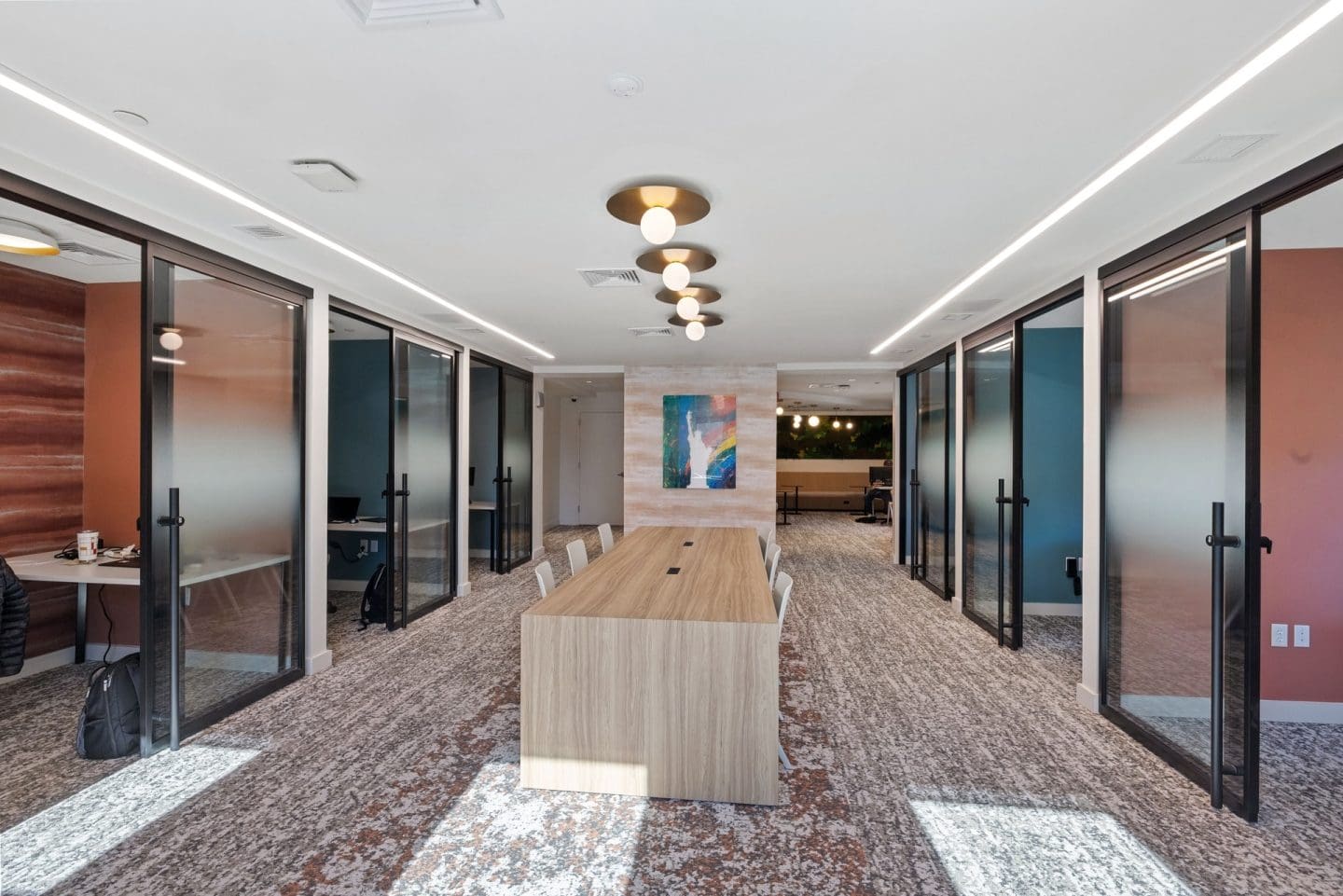 A long hallway with glass doors and a wooden bench.