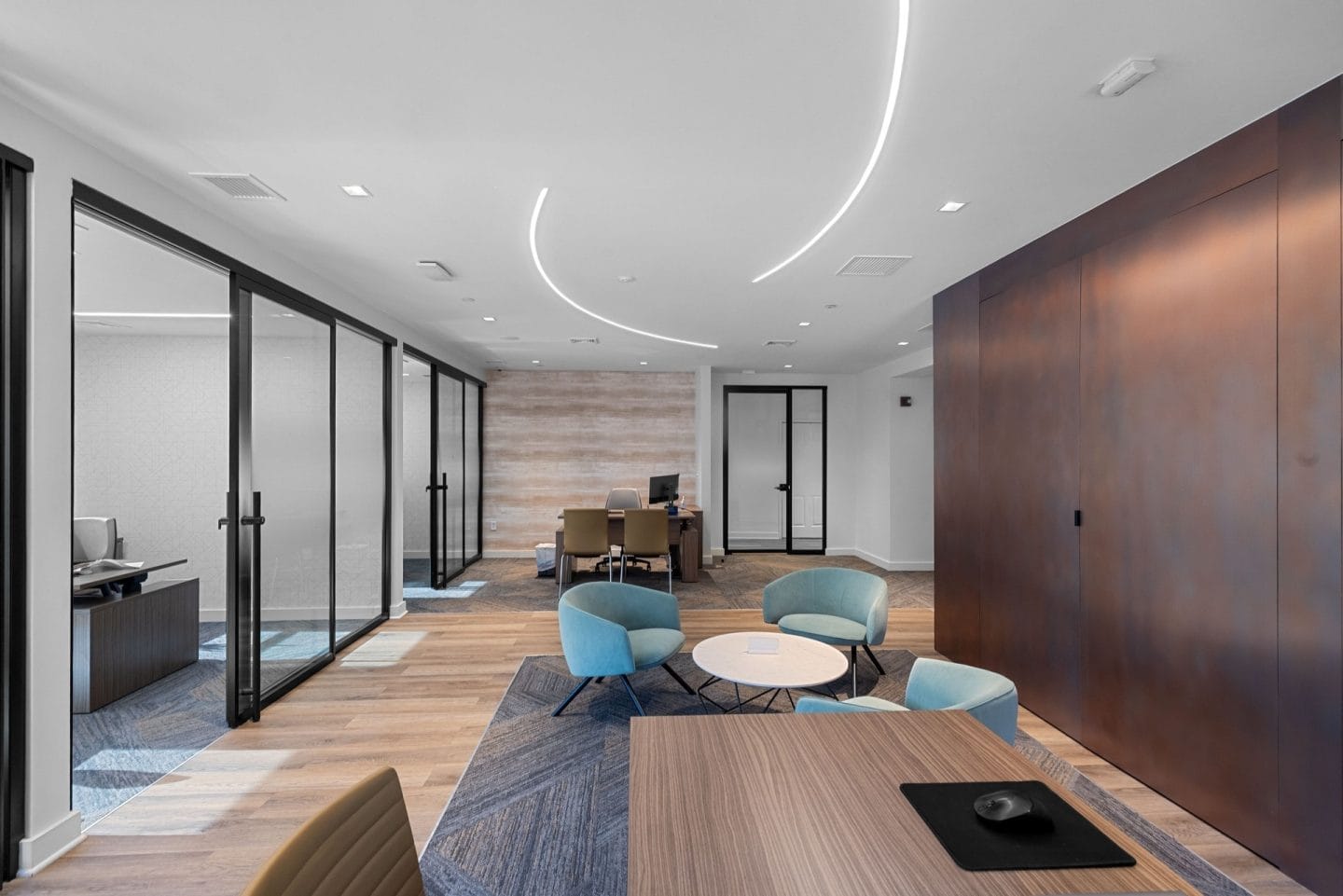A modern office space with a long wooden table and blue chairs.