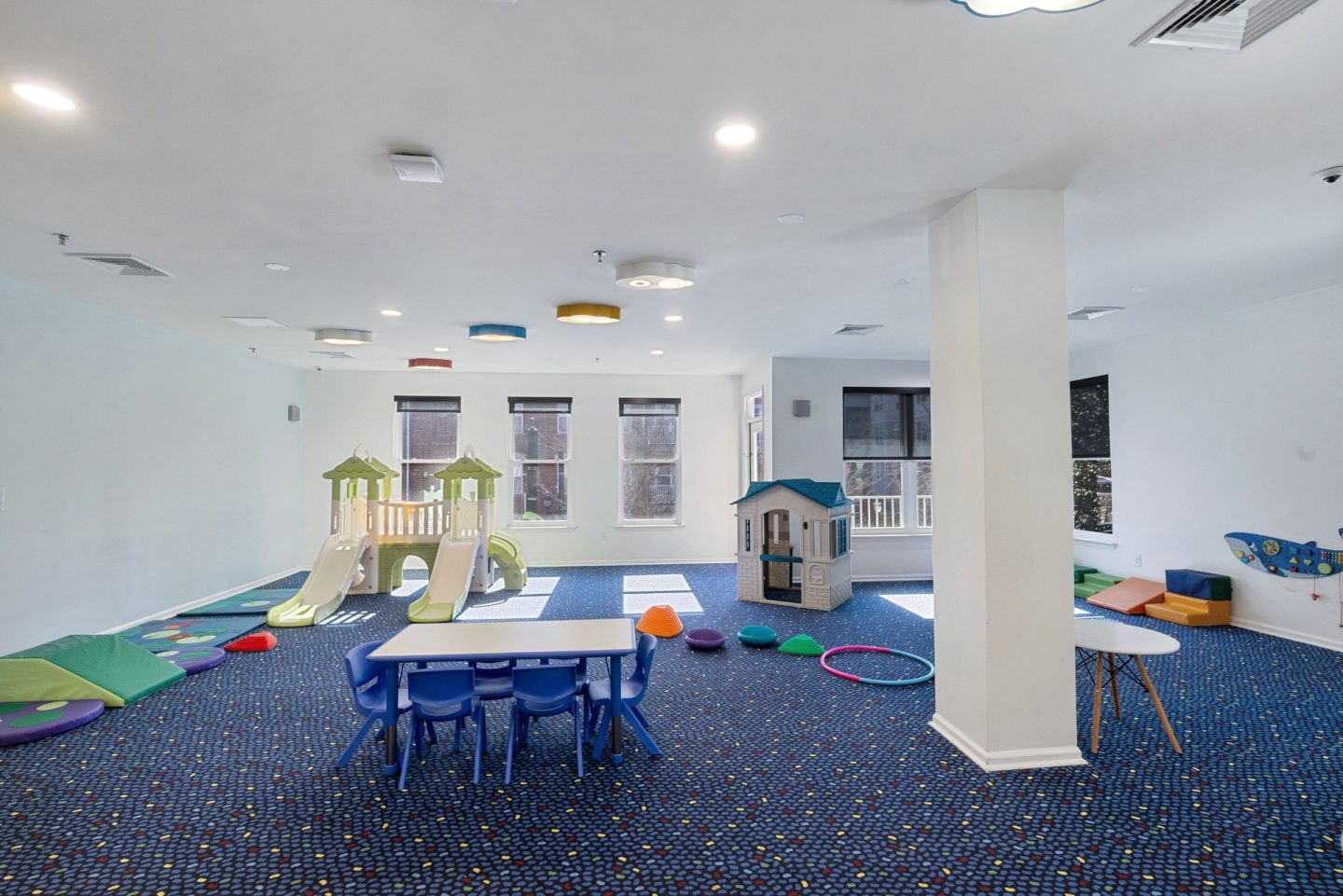 A playroom with a slide, a table and chairs, and a playhouse.