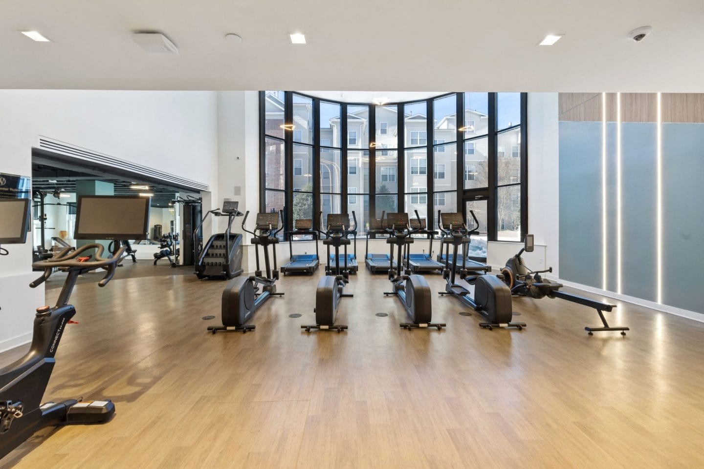 A gym with a row of treadmills and elliptical machines.