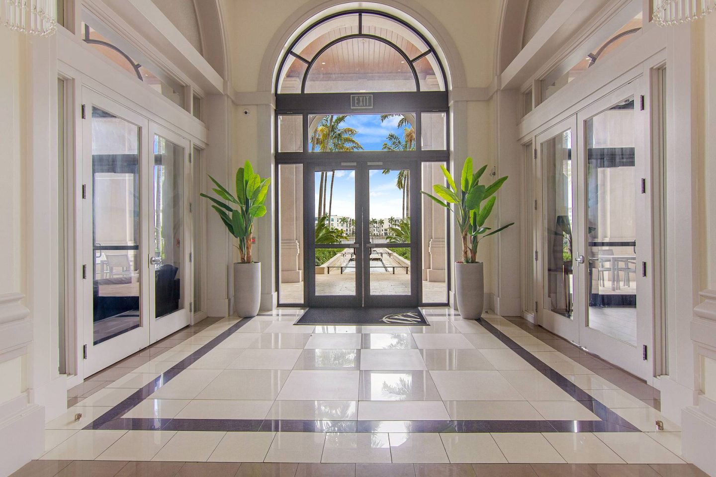 A hallway with a tiled floor and a glass door leading outside.