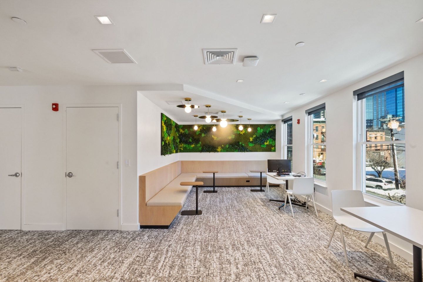 A room with a long table and chairs with a greenery backdrop.