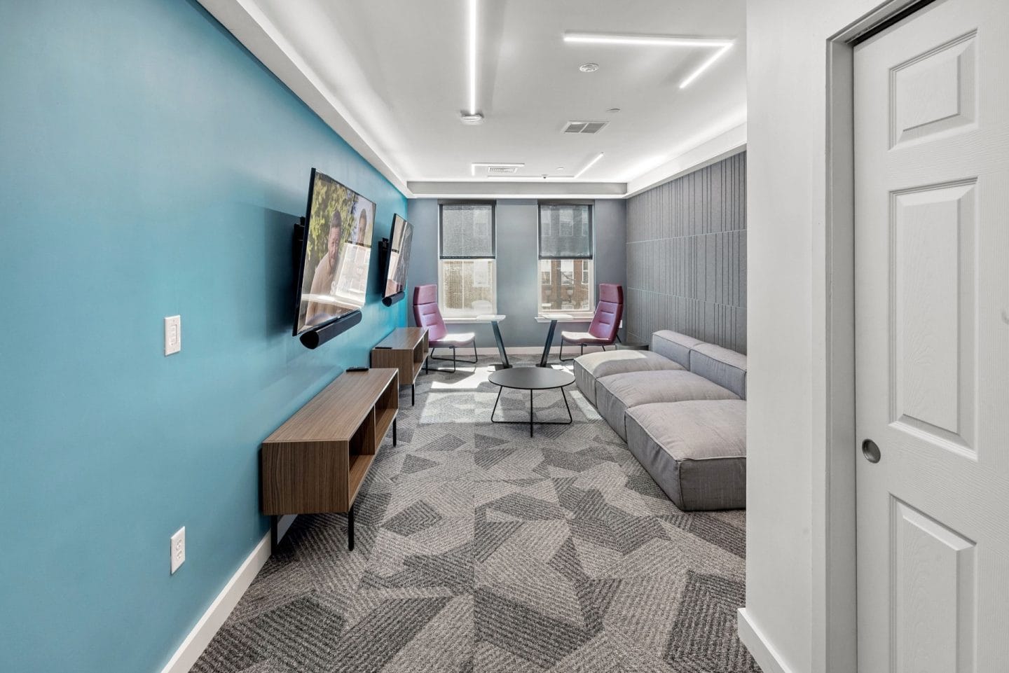 A living room with a grey carpet and a grey sofa.