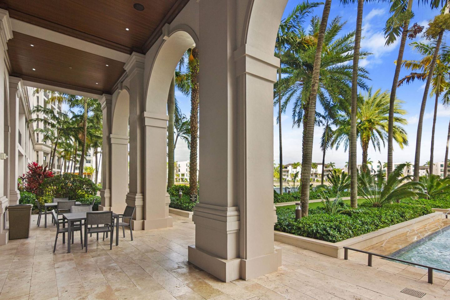 A patio with a table and chairs is surrounded by palm trees.