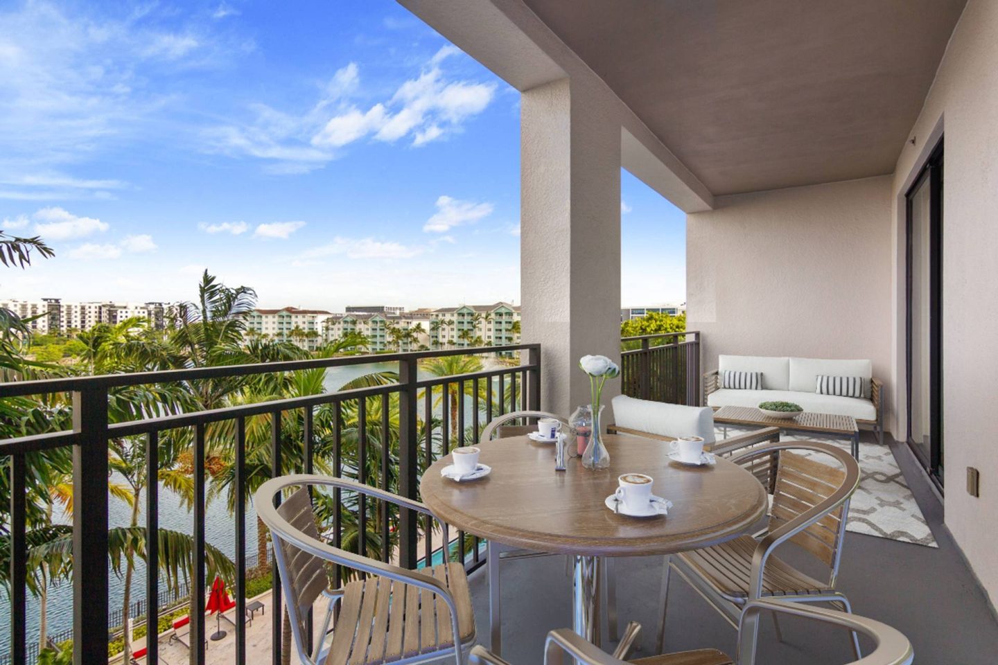 A balcony with a table set for two and chairs around it.