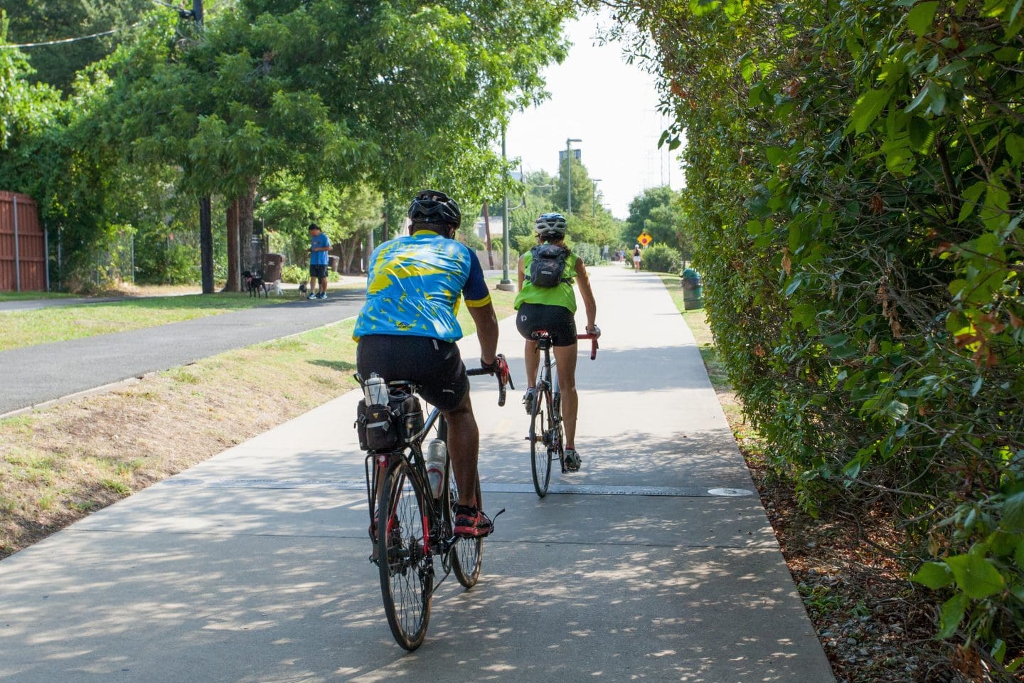 Two people riding bikes on a sidewalk.