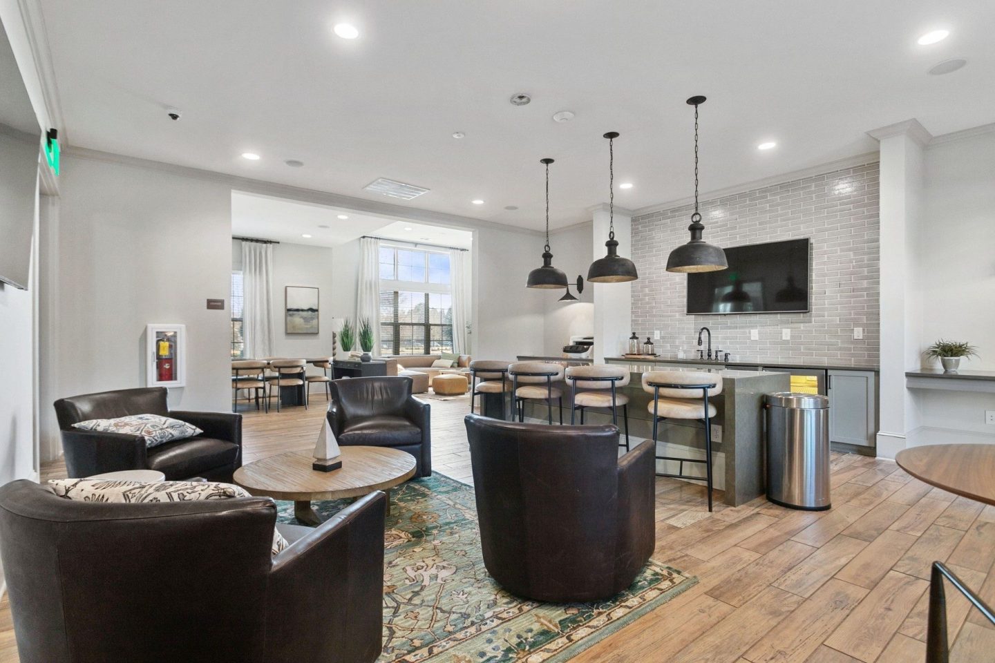 Clubhouse kitchenette at Windsor Sugarloaf 1455 Satellite Blvd Suwanee GA 30024 featuring bar seating lounge chairs a beverage station pendant lighting and open space for resident gatherings