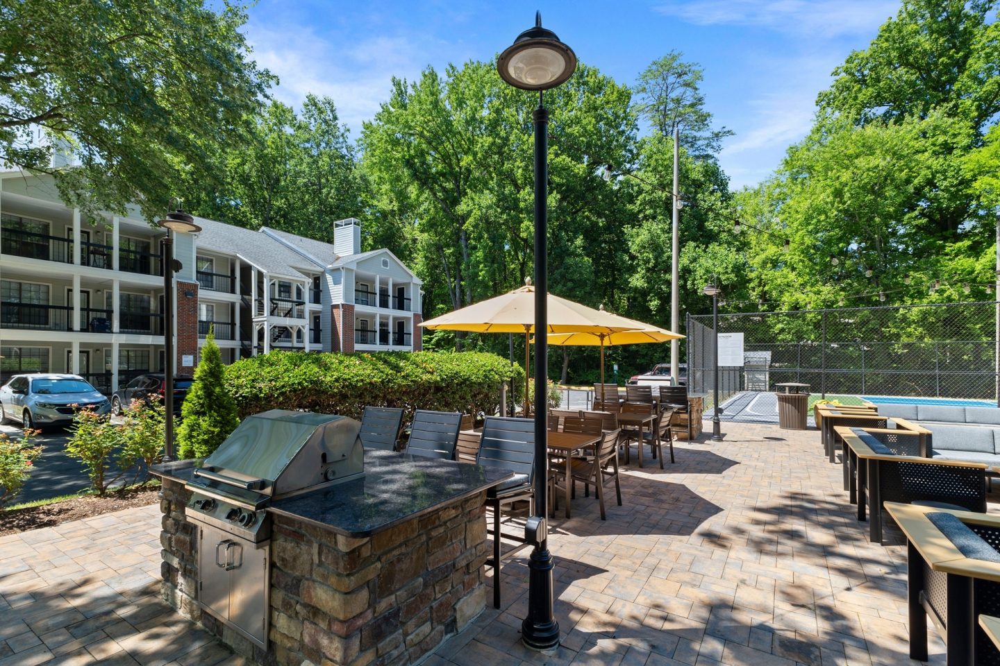 A patio with a table and chairs and a yellow umbrella.