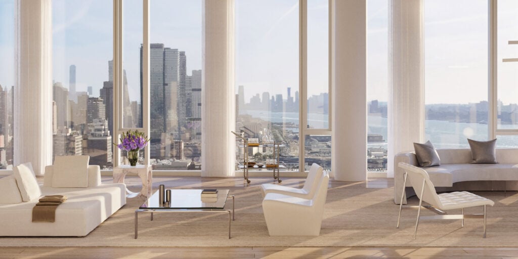 A modern living room with floor-to-ceiling glass walls, allowing natural light to fill the space, featuring a sleek sofa set and contemporary furnishings for a stylish, open feel.