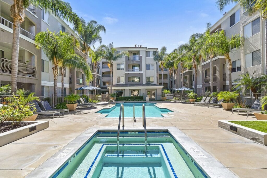 A serene pool located in the park, bordered by lush greenery at the edge of the courtyard, inviting relaxation and tranquility.