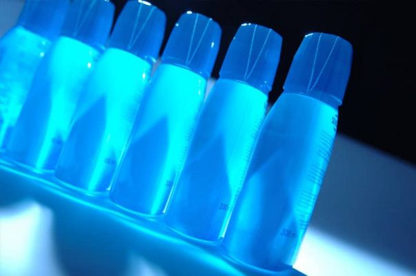Precision plastic bottles aligned under UV light for manufacturing efficiency and process optimization.