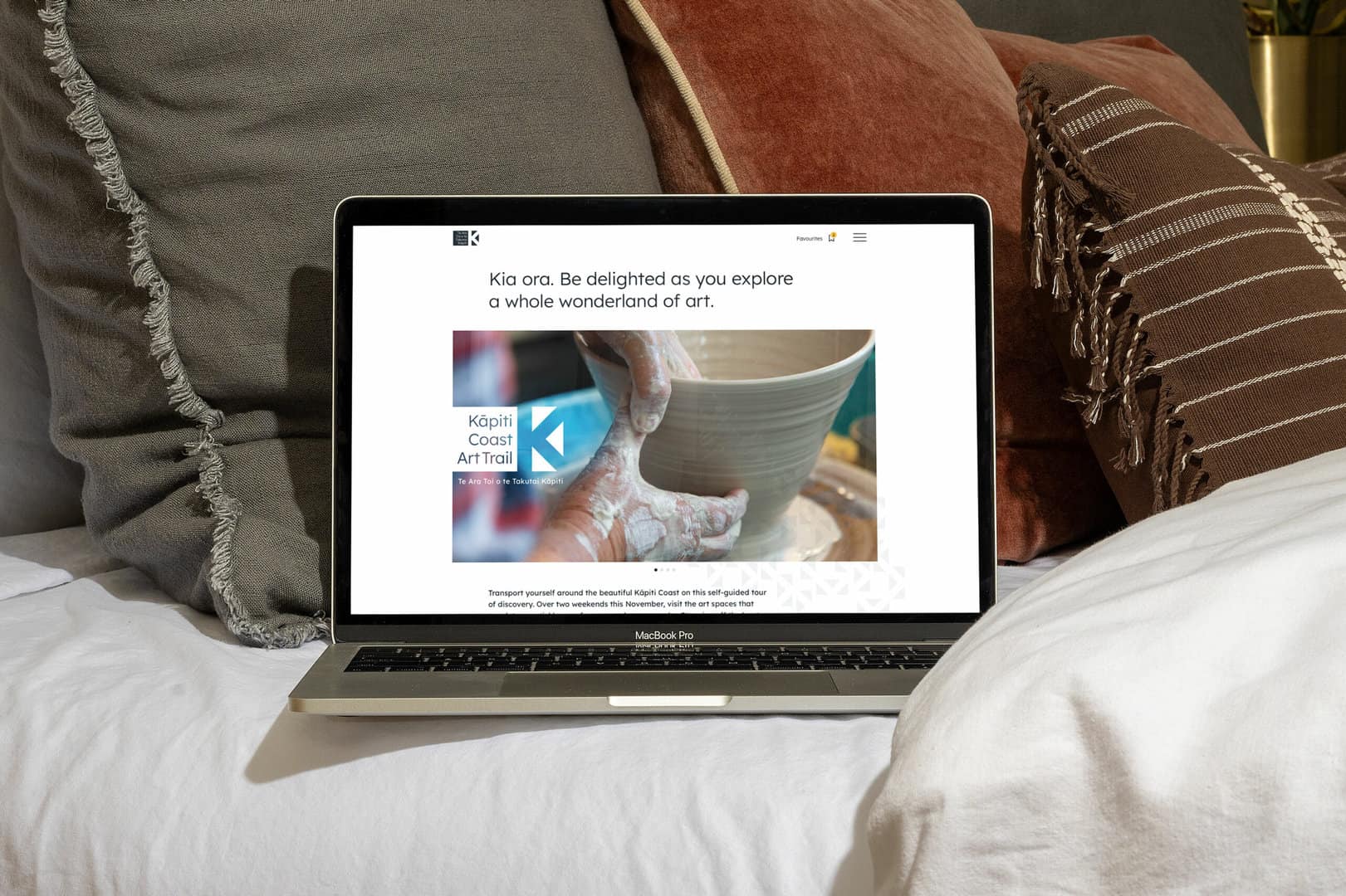 A laptop is on a bed with pillows and pillows.