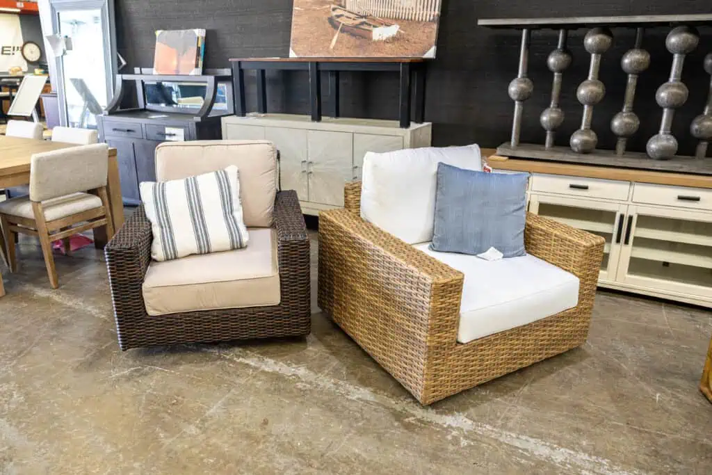 Two wicker armchairs with cushions in a furniture store.