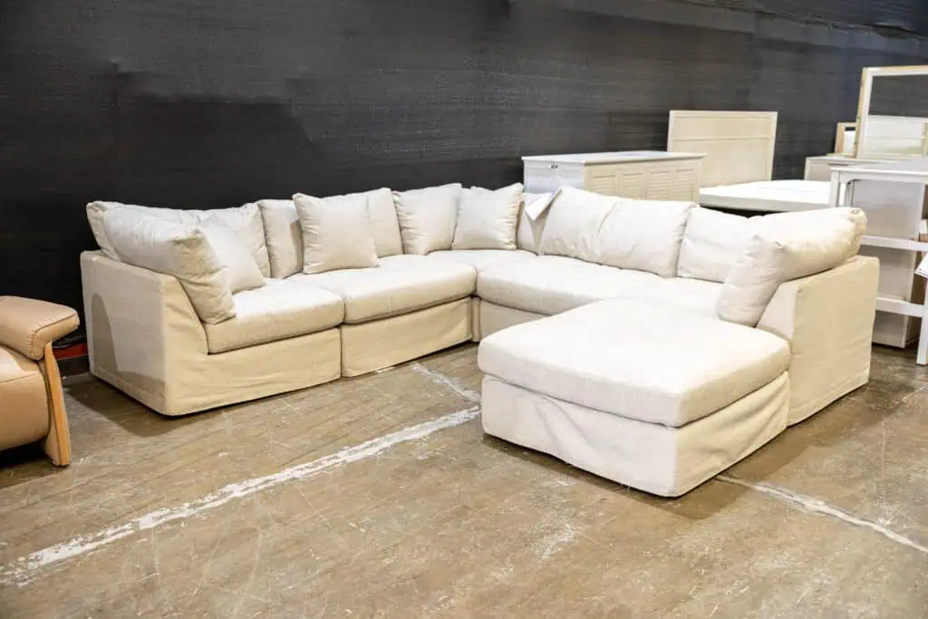 Cream-colored sectional sofa with multiple cushions in a furniture store.