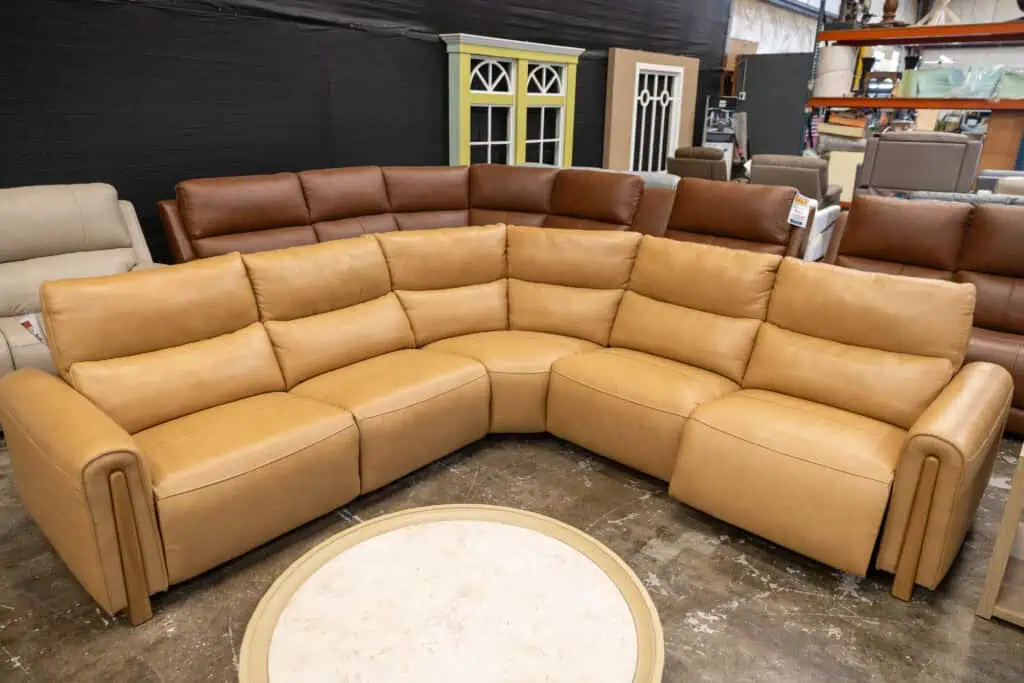 Large tan sectional sofa with multiple cushions in a furniture store.