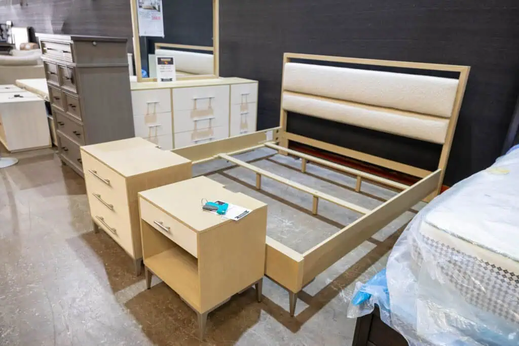 Unassembled bed frame with headboard and matching nightstands in furniture store.