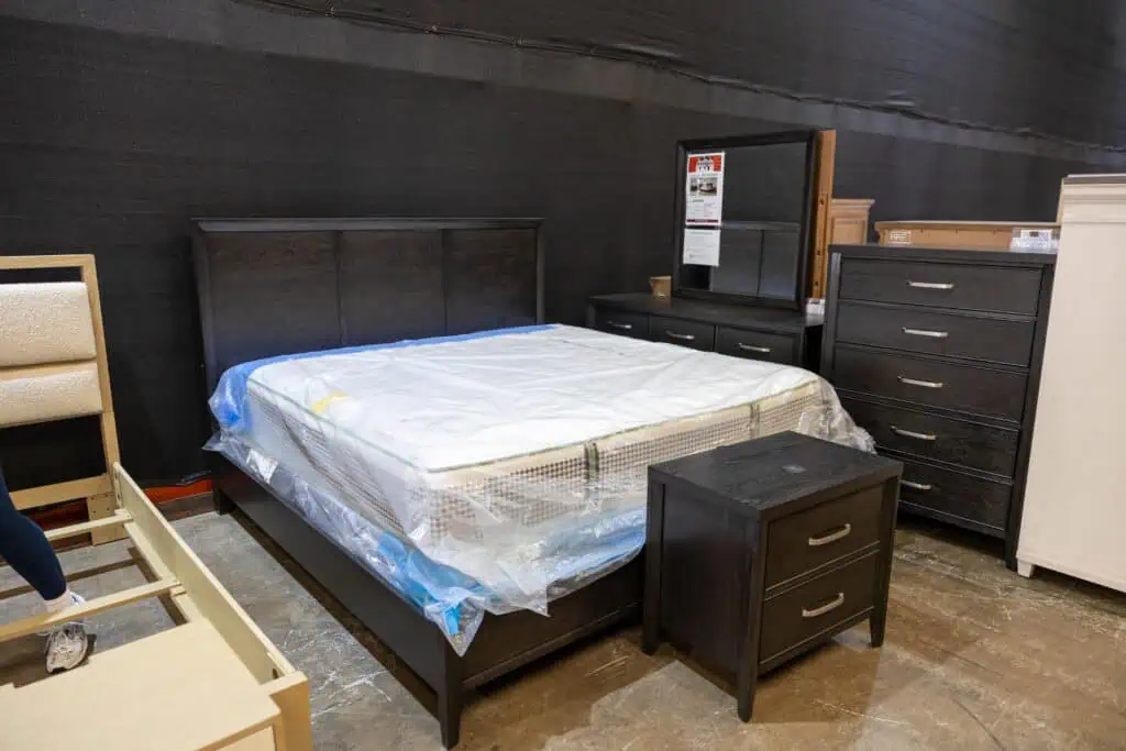 Bedroom furniture including a bed, nightstand, dresser, and mirror displayed in a store.