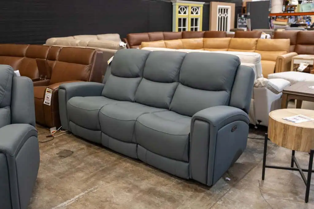 Gray reclining sofa in furniture store with other sofas around it.
